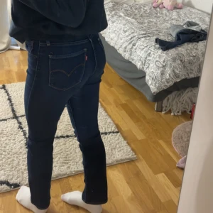 Levi's 724 High Rise Straight jeans - Säljer ett par mörkblå Levi's 724 High Rise Straight jeans i klassisk modell. Jeansen har hög midja, raka ben och snygga kontrastsömmar. Tillverkade i stretchig denim för en bekväm passform. Perfekta för dig som gillar en tidlös och clean look.