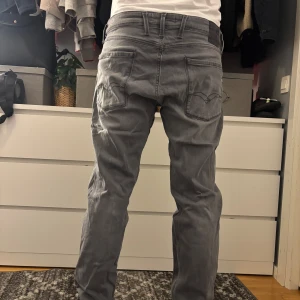 Grå jeansbyxor från Replay - Säljer ett par grå jeansbyxor från Replay med klassisk femficksdesign och raka ben. Byxorna har normal passform och är tillverkade i mjukt bomullsmaterial. Snygga detaljer på bakfickorna och diskret Replay-logga vid sidan. Priset är inte hugget i sten så bara o skriva om du har funderingar 