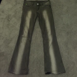 Grå booty bei low jeans  - Säljer ett par grå jeans från Weekday, Cheap Monday med bootcut-modell och snygga slitningar längs benen. Jeansen har klassisk femficksdesign och en cool, lite blekt look framtill och baktill. De är väl använda men inga större defekter.