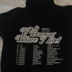 Svart Hov1 hoodie med tryck - Svart hoodie från Hov1 med stort vitt tryck på ryggen där det står 'Vi Dansar Vidare I Livet' och turnédatum