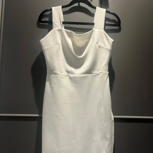Vit kort klänning - Säljer en stilren vit klänning i storlek 36. Klänningen har breda axelband, draperad halsringning och är figurnära. Använd en gång på en skolavslutning men passar till vardags också. 