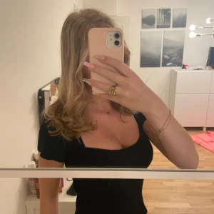 Svart croppad topp - Säljer en svart croppad topp med korta ärmar och fyrkantig urringning. Perfekt för att styla med jeans eller kjol. Enkel men ändå snygg detalj med den fyrkantiga halsen. Skulle tro att det är storlek S.