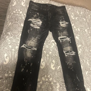 Svarta distressed jeans Supply & Demand - Säljer min sons nästan helt oanvända svarta jeans från Supply & Demand med slitna detaljer, stora hål och vit färgstänk på både fram- och baksida. Köpta på JD för  2 månader sedan.. Säljs för 500kr