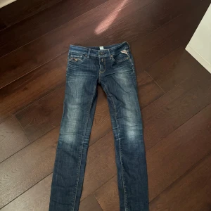 Replay skinny jeans blå, stl 26 - Snygga blå skinny jeans från Replay i klassisk tvätt med slitningar och kontrastsömmar. Modellen har fem fickor, låg midja och smal passform hela vägen ner. Perfekta till sneakers eller boots och funkar året runt.
