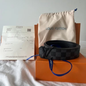 Svart Luviton bälte - Snyggt luviton bälte i klassiska Damier Graphite-mönstret. Svart och grått rutigt skinn med mattsvart luviton spänne. Perfekt accessoar för att lyfta din outfit med exklusiv känsla. Kommer med dustbag och originalbox.