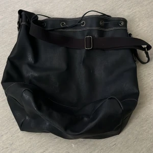 Svart axelväska från Esprit i skinn - Stor svart axelväska från Esprit i mjukt skinn med justerbar axelrem och snygga kontrastsömmar. Väskan har snörning upptill och metallöglor. 