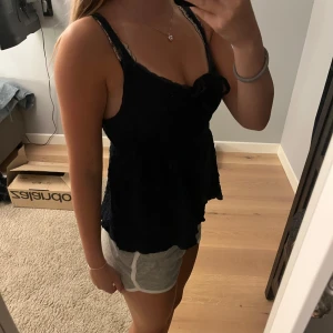 Mörkblå spetsig linnetopp med rosett - Supersöt svart linnetopp med tunna axelband och spetsdetaljer. Toppen har en liten rosett framtill och lätt volangig nederkant. Köpt på Gina Tricot. Skriv för fler frågor 