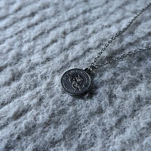 Memento Duality Silver Necklace - Stainless steel necklace with a small engraved pendant reading Memento Mori and Amor Fati, accented by a subtle skull motif. Chain length: 44 + 6 cm • Pendant diameter: 1.3. 