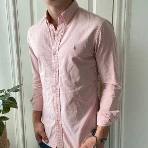 Ralph Lauren skjorta rosa  - Rosa Ralph Lauren skjorta i M slim fit. Inga defekter riktigt förutom att den tidigare ägaren hade nog haft solkräm på sig så inuti har den minimala fläckar som ni ser på sista bild. Modellen är 180,75 kg. Kom med frågor👍