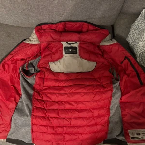 Sail racing hybrid - Hejsan! Säljar en gammal modell av sail racing hybrid. Jackan är använd men är i nästintill nyskick förutom 2 super små hål där bak. Jackan är perfekt nu till hösten och början av vintern och är även i färgen grå vilket är ganska sällsynt på just denna modellen!