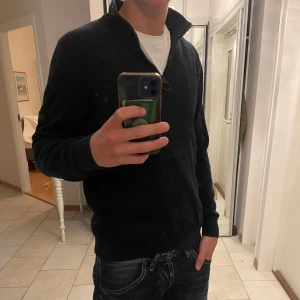 Marinblå kvart zip tröja från Barbour - Säljer en stilren marinblå tröja från Barbour med half zip och ribbade muddar. Tröjan har lång ärm och en liten logotyp på vänster ärm. Perfekt för dig som gillar sportig och clean stil.