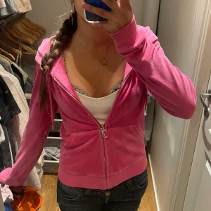 Juicy Couture rosa hoodie  - Säljer en rosa hoodie från Juicy Couture i mjuk velour. Tröjan har huva, långa ärmar och en snygg dragkedja med J-logga. Fickor framtill och ribbade muddar ger en chill vibe. Perfekt för dig som vill ha den klassiska Y2K-stilen. Liten fläck på armen som man inte äns märker😊