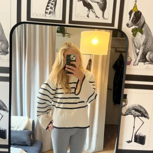 Randig stickad tröja från Gina Tricot - Superfin stickad tröja från Gina Tricot i vitt med svarta ränder. Tröjan har breda, långa ärmar och en lite boxig passform. Ribbstickade muddar och högre halsringning ger en chill vibe. Perfekt att slänga på sig när det är lite kyligt ute.