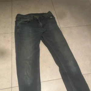 Mörkblå jeans från Nudie Jeans - Säljer ett par mörkblå jeans från Nudie Jeans med klassisk femficksdesign och snygga slitningar. Jeansen är i en slim Model, och jag skulle säga att dom passar folk som är runt 160- till 165 