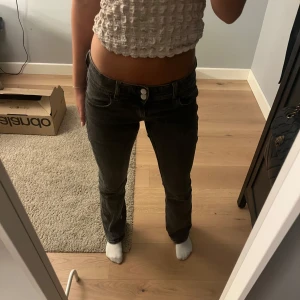 Bootcut svarta jeans med låg midja - Säljer ett par svarta bootcut jeans med låg midja och snygga detaljer på bakfickorna. Jeansen är från Gina. De har inga defekter. Skriv för mått.