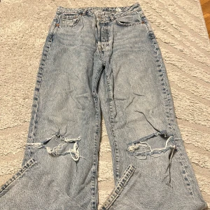 ljusblå slitna jeans -  jeans med klassisk rak passform och tydliga slitningar och hål på båda knäna. Jeansen har fem fickor, knappgylf och är tillverkade i robust denim. Perfekta för en avslappnad och trendig look.