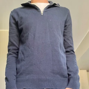 Mörkblå half zip-tröja från Riley - Snygg mörkblå tröja från Riley med half zip-dragkedja och hög krage. Tröjan är långärmad och har en klassisk, stilren look. Storlek S, passar