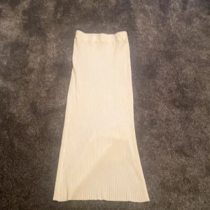 Vit ribbad långkjol från Chica London - Säljer en snygg vit ribbad långkjol från Chica London i storlek S/M. Kjolen har en rak passform, stretchigt stickat material och en liten slits nertill för extra rörelsefrihet. Perfekt för dig som gillar stilrena och enkla plagg med en modern touch. Inte använt💞