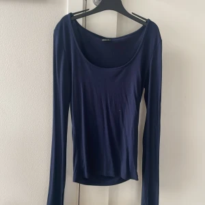 Mörkblå långärmad topp Gina Tricot - En stilren mörkblå långärmad topp från Gina Tricot i storlek XS. Toppen har en djup rundad urringning och är figurnära i modellen. Perfekt att matcha med jeans eller kjol för en clean look. Säljer den för att den är lite för stor för mig.