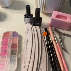 Nagelkit med glitter och penslar - Nagelkit med glitter i olika rosa och silvriga nyanser, flera nagelfilar, penslar med svarta och rosa skaft samt gel-lack från SJP och Tomicca. Perfekt för att skapa kreativa nageldesigner hemma. Går att köpa separat, har även geleer