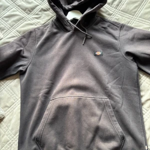 Mörkgrå hoodie från Dickies M - Säljer en mörkgrå hoodie från Dickies i storlek medium. Klassisk modell med huva och snörning, samt stor magficka framtill. Liten Dickies-logga på bröstet. Perfekt för dig som gillar streetwear och enkel stil.