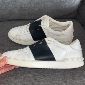 Valentino Open sneakers vit/svart skinn - Snygga Valentino Open sneakers (säljs otroligt mycket kopior på plick men dessa är självklart äkta) i vitt skinn med bred svart läderdetalj över vristen. Klassisk rund tå, platt sula och diskret logga på plösen. Lite målade med vit skofärg av tidigare ägare men det är inget som man tänker på. (OBS sulorna är bytta för bättre kvalitet men det är inget som syns eller har någon påverkan). Suveräna skor, bara att höra av sig om minsta fundering.😁