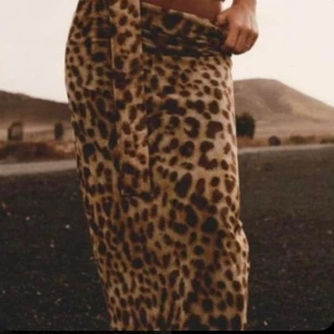 Leopardmönstrad långkjol från Zara - Snygg långkjol från Zara med leopardmönster i bruna och svarta toner. Kjolen har en tajt passform och är fodrad med ett tunt innerfoder. Perfekt för dig som vill sticka ut med en trendig och djurinspirerad look. Använd två gånger