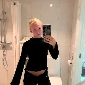 Svart långärmad croppad tröja - Säljer en svart långärmad croppad tröja med enkel design och rak passform. Tröjan har en något lös siluett och är perfekt för dig som gillar minimalistisk stil. Passar till både jeans och kjol för en clean look.