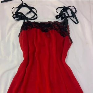 Röd top/minidress med spets från Secret Treasures - Supersöt röd minidress från Secret Treasures med svarta knytband och vacker svart spets upptill. Axelbandslös känsla med romantiska detaljer.