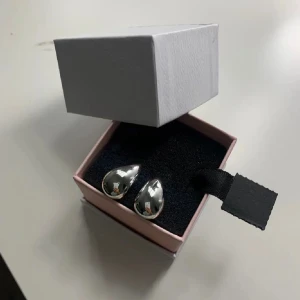 Droppformade silvriga örhängen - Snygga örhängen i droppformad design med blank, silvrig yta. Perfekta för dig som gillar stilrena och moderna accessoarer. Kommer i en fin ask, redo att ges bort eller användas direkt.