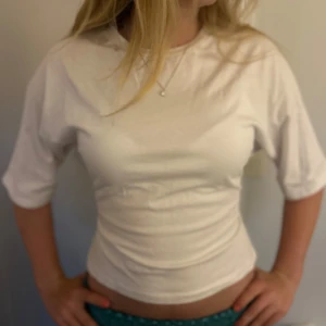 Vit bolerotopp med knyt från Nelly - Supersnygg vit bolerotopp från Nelly med halvlånga ärmar och öppen rygg som knyts baktill. Toppen är croppad och gjord i mjuk bomull, perfekt för en trendig look. Enkel att styla med både jeans och kjol.