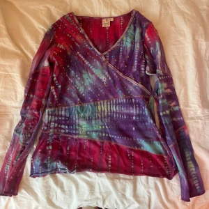 Färgglad omlottopp med pärlor - Säljer en  omlottopp i tie-dye stil Toppen har v-ringning, långa ärmar och är dekorerad med små paljetter, skriv om ni har frågor eller vill ha fler bilder