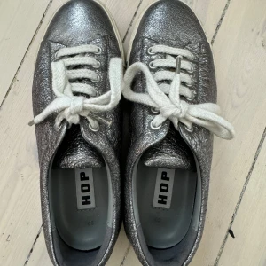 Silvriga HOPE sneakers  - Säljer mina snygga silvriga sneakers från HOPE med vit hög sula och grova vita snören. Skorna är i storlek 39, men passar mig som vanligtvis har storlek 40. Skorna är sparsamt använda och i väldigt bra skick💕