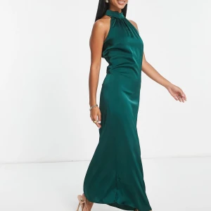 Grön långklänning i satin - Snygg smaragdgrön långklänning i satin med hög hals och ärmlös design💚 Klänningen har en elegant, slät siluett och lätt glansigt material som ger en lyxig känsla. Perfekt för studentbal eller finare tillfällen! Aldrig använd, har prislapp kvar!🫶🏼
