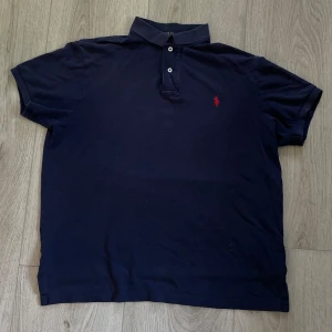 Pikétröja från Ralph Lauren - Klassisk marinblå piké från Polo Ralph Lauren med röd broderad logga på bröstet. Storlek L men passar M/L. Hör av er vid frågor.