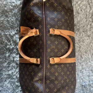 Louis Vuitton Keepall 60 Monogram Resväska - Nypris idag: 26 600kr. Storlek 60, därmed största modellen. Bra vintage skick. Säljer en klassisk Louis Vuitton Keepall resväska i brunt monogrammönster med ljusbruna skinnhandtag och detaljer. Väskan har dragkedja och ikoniska LV-loggan över hela ytan. Perfekt storlek för weekendresor och riktigt snygg att bära med sig.
