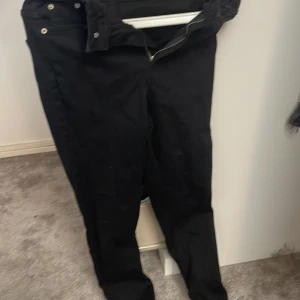 Svarta jeans från NA-KD med råa benslut - Svarta jeans från NA-KD med klassisk femficksdesign, dragkedja och knapp framtill. Jeansen har råa, fransiga benslut för en edgy look. Tillverkade i bomullsmix med en rak passform som funkar till allt. Dom är skinni 