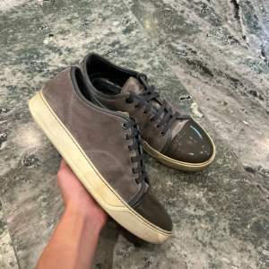 Snygga grå sneakers med brun tå och snörning. Skorna har en vit sula och är tillverkade i mocka med detaljer i syntet. Perfekta för en avslappnad stil. Från lanvin 