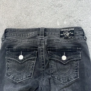 Grå/svarta bootcut jeans från True Religion - Säljer mina grå/svarta bootcut jeans från True Religion i Becca🥰 mid rise men skulle säga att dom är low waist dom sitter ganska långt under naveln, knappt använda. Storlek 26 passar mig som har storlek xs-s 