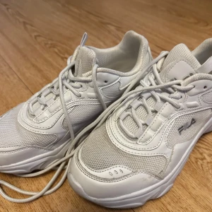 Vita sneakers från Fila - Snygga vita sneakers från Fila med klassisk design. Skorna har snörning och en chunky sula som ger extra komfort. Perfekta för en stilren look. Skorna är sparsamt använda men såklart blir vita skor smutsiga, har rengjort den så gott jag kunde. Innersulan är helt ny då annan sula använts. 