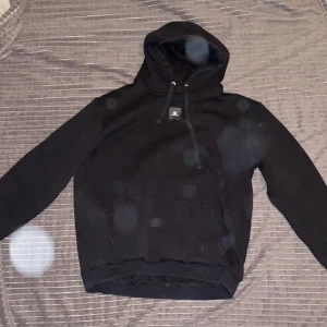 Svart hoodie från The Cool Elephant - Säljer en svart hoodie från The Cool Elephant med en färgglad grafisk design på ryggen. Tröjan har en klassisk känguruficka. 