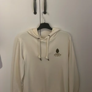 Beige Hoodie från Morris - Säljer en unik beige hoodie från Morris med broderad logga på bröstet. Tröjan har en klassisk huva och snygga snören. Perfekt för en avslappnad look. Hör gärna av dig vid frågor eller funderingar! Mvh Melker