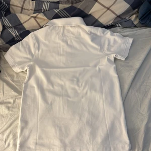 Vit pikétröja från Cutter & Buck - Säljer en stilren vit pikétröja från Cutter & Buck i storlek S skulle även passa M. Tröjan har korta ärmar och en klassisk krage med knappar. Perfekt för en avslappnad och snygg look.