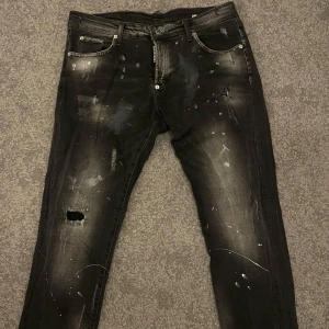 Svart/grå jeans från Dsquared2 - Snygga svarta jeans från Dsquared2 med slitna detaljer och en cool, tvättad look. Perfekt för alla sorters klädstilar
