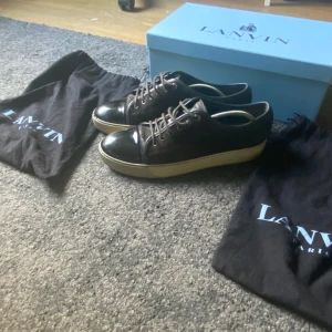 Svarta sneakers från Lanvin - Snygga svarta sneakers från Lanvin med en stilren design. Skorna har en vit sula och klassisk snöring skorna är storlek uk 8 vilket motsvarar ungefär 42-43 skorna är lite använda men är fortfarande i bra skick. Vi kan alltid diskutera om priset och var inte rädd å ställa frågor om du har några!