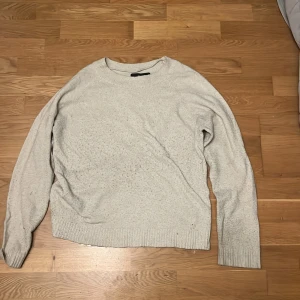 Beige stickad tröja från Vero Moda - Säljer en mysig beige stickad tröja från Vero Moda. Tröjan har en enkel design med långa ärmar och ribbade kanter vid ärmslut och nederkant. Den är väldigt nopprig och har två små hål.  Hör av dig vid intresse! 😊
