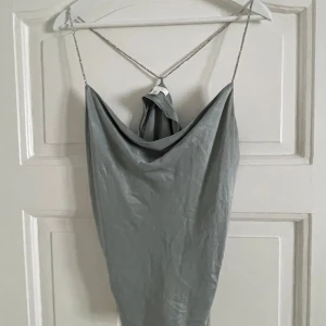 Topp från H&M - Snygg grå/grön topp från H&M med tunna glittriga axelband och draperad framsida. 