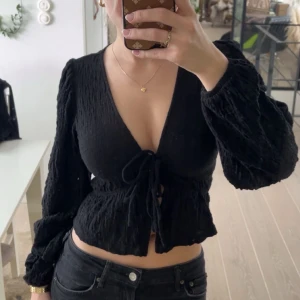 Svart knytblus - Snygg svart blus med knytning framtill och v-ringning. Använd 1 gång. 