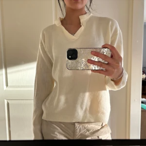Vit tröja med unik krage - Säljer en stilren vit tröja med en unik krage och långa ärmar. Perfekt för en minimalistisk look. Tröjan har ribbade muddar vid ärmslut och nederkant.