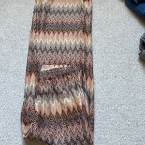 Mönstrade vida byxor i stickad look - Säljer ett par riktigt snygga vida byxor som kallas orrebyxor,  med zigzag-mönster i beige, brunt, rosa och olivgrönt. Byxorna har resår i midjan och är gjorda i ett stickat material som känns både mjukt och luftigt. Perfekta för dig som gillar retrovibbar och vill sticka ut.